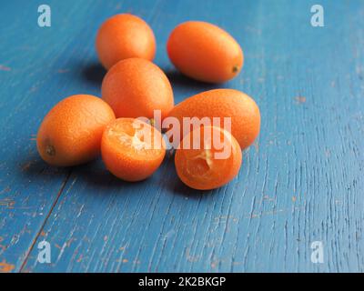 Kumquat biologici freschi su un rustico tavolo da cucina in legno Foto Stock