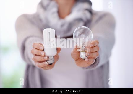 Mantenere le luci accese più a lungo. Un'immagine ritagliata di una donna che tiene due lampadine diverse. Foto Stock