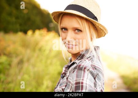 Rilassante bellezza di campagna. Bella giovane donna in un campo mentre indossa una paglia fedora. Foto Stock