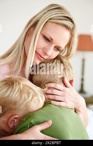 Quando i miei figli sono tristi, im triste. Una madre sconvolgente che abbraccia i suoi due figli. Foto Stock