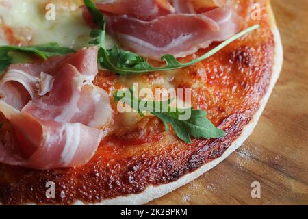 Pizza con prosciutto affumicato e Rucola su sfondo di legno Foto Stock