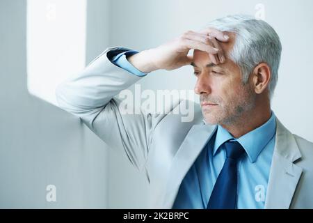 È il momento di lavorare. Colpo di un uomo d'affari maturo stressato-fuori che guarda appoggiato contro un muro. Foto Stock