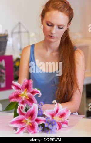 Un occhio per la forma e la bellezza. Bella giovane donna che arrangiano le lilla in un bouquet floreale. Foto Stock