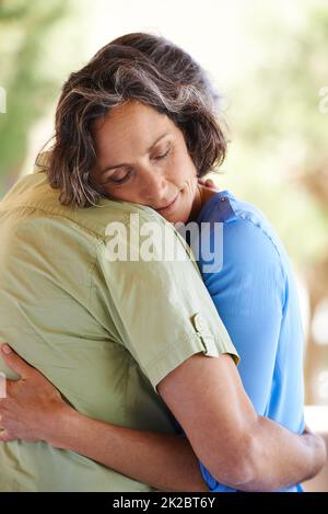 Sicuro in amori braccia. Un taglio corto di una coppia affettuosa che abbraccia all'aperto. Foto Stock