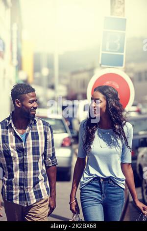 Il primo dovere dell'amore è ascoltare. Scatto di una coppia felice che cammina attraverso una zona urbana. Foto Stock