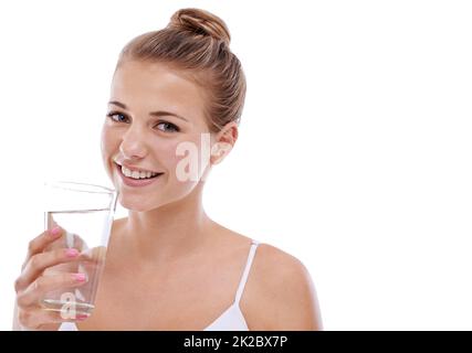 Il suo segreto di bellezza. Una ragazza giovane carina con la pelle perfetta bere acqua mentre isolato su bianco. Foto Stock