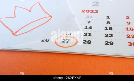 Primo piano di un calendario cartaceo il 27 aprile 2022 con sfondo arancione e corona disegnata a mano nei colori tradizionali della celebrazione del giorno del Re nei Paesi Bassi Foto Stock