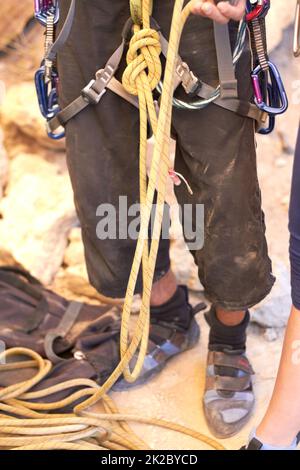 Come ottenere ramped dentro. Scatto corto di un giovane scalatore di roccia in piedi e regolare le sue imbracature. Foto Stock