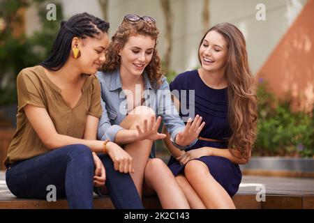 Ooh ragazze, controllare questo manicure. Un gruppo di giovani donne sedute all'aperto ammirando le unghie di un amico. Foto Stock