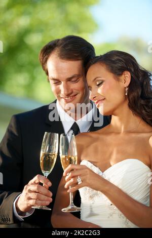 Heres al nostro amore. Vista spezzata di una giovane sposa e sposo in piedi insieme e tostare il loro matrimonio. Foto Stock