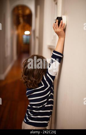 Salvare il pianeta un interruttore alla volta. Un colpo corto di un ragazzino che spegne una luce in casa sua. Foto Stock