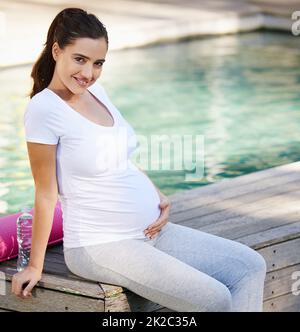 Sentirsi totalmente rilassati dopo aver fatto yoga. Shot di una giovane donna incinta seduta con il suo tappeto yoga all'esterno. Foto Stock