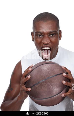 Il suo gioco su. Studio girato di un determinato giovane giocatore di basket gridando mentre tiene un basket. Foto Stock