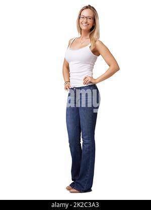 Incandescente con sicurezza. Giovane donna fiduciosa in jeans blu in piedi con le mani sui fianchi. Foto Stock