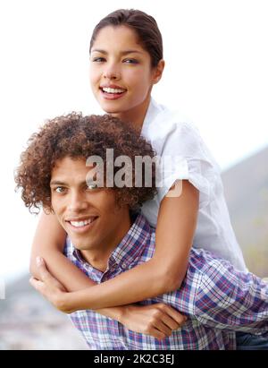 Abbastanza forte per entrambi. Scatto di un bel giovane uomo che dà alla sua ragazza un piggyback all'aperto. Foto Stock