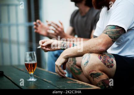 Estate tempo socializzante. Shot di giovani che fumano e bevono. Foto Stock