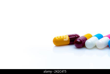 Pillole antibiotiche capsule su sfondo bianco. Resistenza agli antibiotici. Capsule di antibiotico rosso-giallo, blu-bianco e rosa-bianco. Farmaci da prescrizione. Banner farmacia. Prodotti farmaceutici. Foto Stock