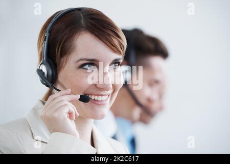 Un atteggiamento amichevole quando si tratta di assistenza al cliente va molto in un ambiente di vendita. Immagine di un giovane e bello agente del servizio clienti che lavora in un ufficio. Foto Stock