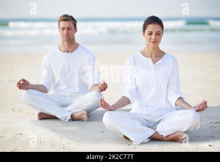 Yoga sul mare. Una giovane coppia che pratica yoga sulla spiaggia. Foto Stock