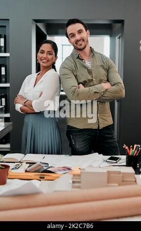 Insieme costruiamo sogni. Scatto ritagliato di due giovani architetti che lavorano insieme in un ufficio moderno. Foto Stock