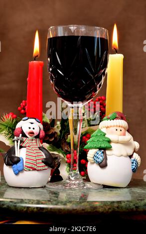 Bicchiere di vino di Natale con figure natalizie Foto Stock