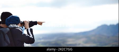 Ammirando la vista maestosa. Una giovane coppia che guarda la vista attraverso il loro binocolo durante un'escursione. Foto Stock