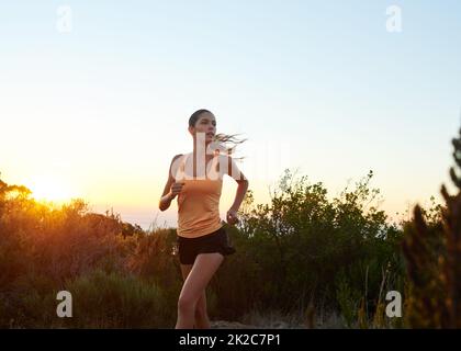 Allenati come una bestia, assomiglia a una bellezza. Scatto corto di una giovane donna che fa jogging all'aperto. Foto Stock