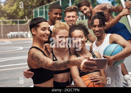 Prendiamo uno dei migliori team. Girato di un gruppo di giovani sportivi che prendono selfie insieme su un campo sportivo. Foto Stock