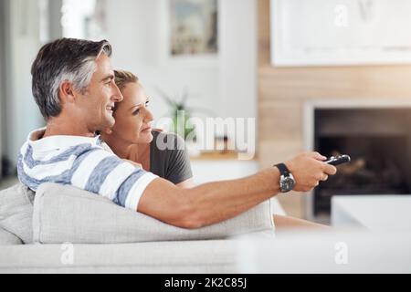 Un altro episodio. Scatto corto di una coppia matura affettuosa coccolarsi sul divano mentre si guardano i film a casa. Foto Stock