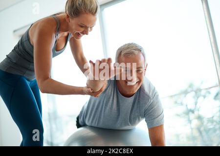 I vostri obiettivi sono a portata di mano. Scatto corto di una donna matura attraente che aiuta il suo marito con il suo workout a casa. Foto Stock