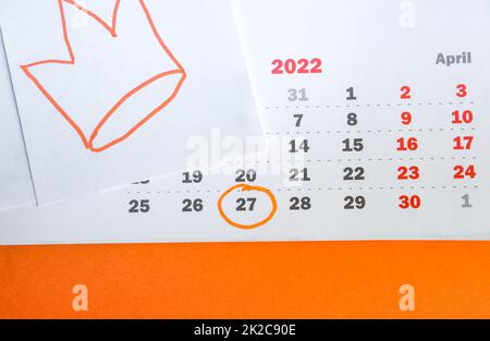 Primo piano di un calendario cartaceo il 27 aprile 2022 con sfondo arancione e corona disegnata a mano nei colori tradizionali della celebrazione del giorno del Re nei Paesi Bassi Foto Stock