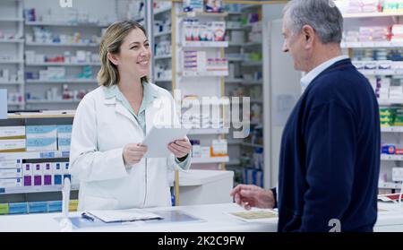 Sempre pronti a offrire le migliori soluzioni. Shot di un giovane farmacista che consegna una prescrizione ad un cittadino anziano in una farmacia. Foto Stock