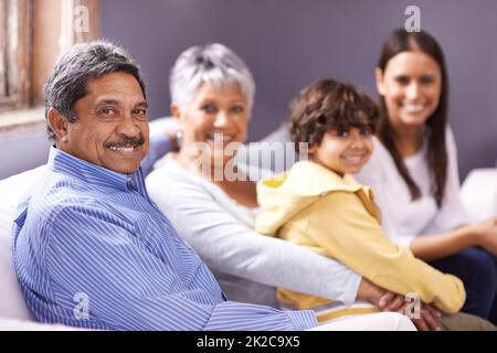 Ci attacciamo insieme. Ritratto di una famiglia che si unisce nel soggiorno. Foto Stock