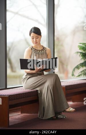 Scegliere il passaggio perfetto. Scatto di una giovane donna vestita elegantemente che legge attraverso una cartella. Foto Stock