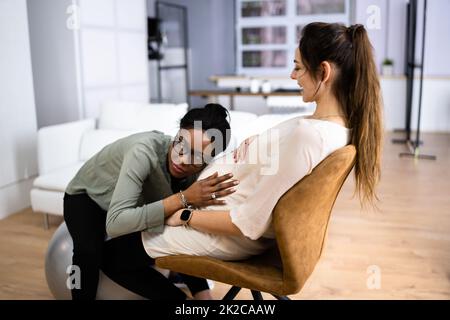 Donna incinta che ha Un massaggio da terapista femminile africano Foto Stock