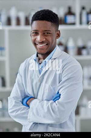 Mantiene sempre fresco. Ritratto di un giovane scienziato maschile allegro in piedi con le braccia ripiegate all'interno di un laboratorio. Foto Stock