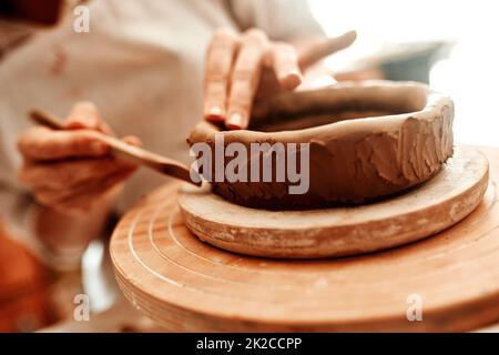 Il suo divertimento e ricompensare per trasformare un pezzo di argilla in arte. Scatto ritagliato di una donna che forma un vaso di argilla nella sua officina. Foto Stock