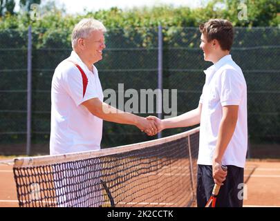 Buon figlio del gioco. Un padre e un figlio scuotono le mani dopo una partita amichevole di tennis. Foto Stock