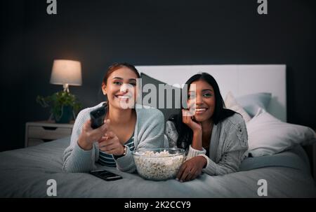 Abbiamo tutto ciò di cui abbiamo bisogno proprio qui. Girato di due giovani donne che mangiano popcorn mentre guardano un film a casa. Foto Stock