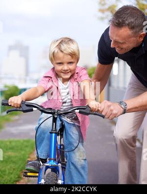 Apprendimento rapido HES. Un padre insegnava a suo figlio giovane di andare in bicicletta. Foto Stock