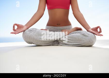 Dando alla sua mente un allenamento. Scatto di una giovane donna meditating mentre fa yoga fuori in una giornata di sole. Foto Stock