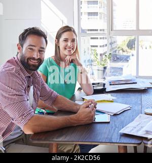 Bene raggiungere il successo insieme. Ritratto corto di due giovani designer seduti nella sala riunioni. Foto Stock