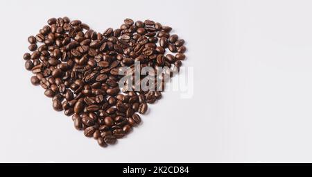 Chi non ama il caffè. Shot studio di chicchi di caffè a forma di cuore su sfondo bianco. Foto Stock