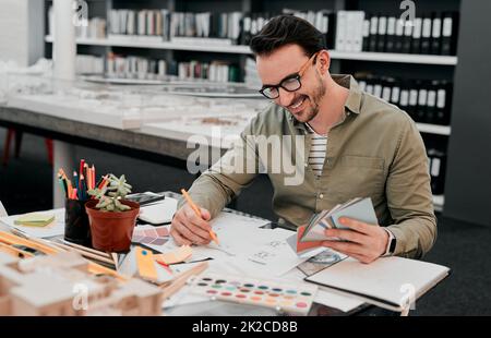 Aveva sempre la vocazione di essere architetto. Ripresa ritagliata di un bel giovane architetto maschile sorridente mentre lavora con alcuni progetti in un ufficio moderno. Foto Stock