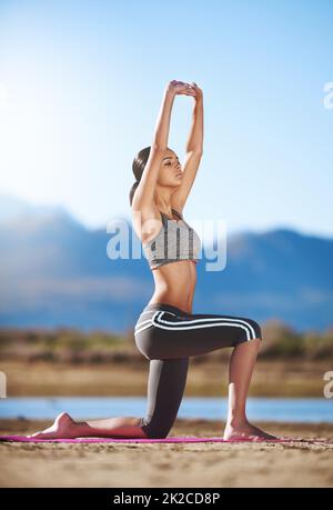 L'energia scorre dove l'attenzione va. Shot di una giovane donna che pratica yoga all'aperto. Foto Stock