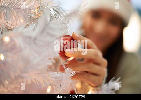 Mettere ogni pezzo nel posto perfetto. Scatto corto di una giovane donna che decora un albero di Natale. Foto Stock