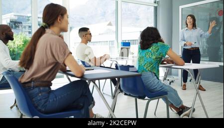 Trading in tempo sprecato. Shot di studenti in aula che hanno una discussione con il professore all'università. Foto Stock