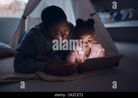 Che cosa state andando leggere la mamma. Scatto di una madre che legge storie sull'ora di dormire con sua figlia su un tablet digitale. Foto Stock