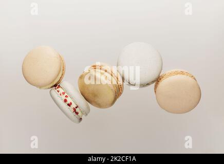 Biscotti bianchi, gialli, dorati al macaron che volano, cadono in movimento o si levitano Foto Stock