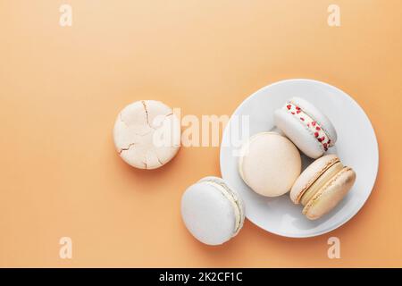 Biscotti al macaron bianchi, gialli e dorati. Piccoli amaretti francesi colorati e dolci Foto Stock